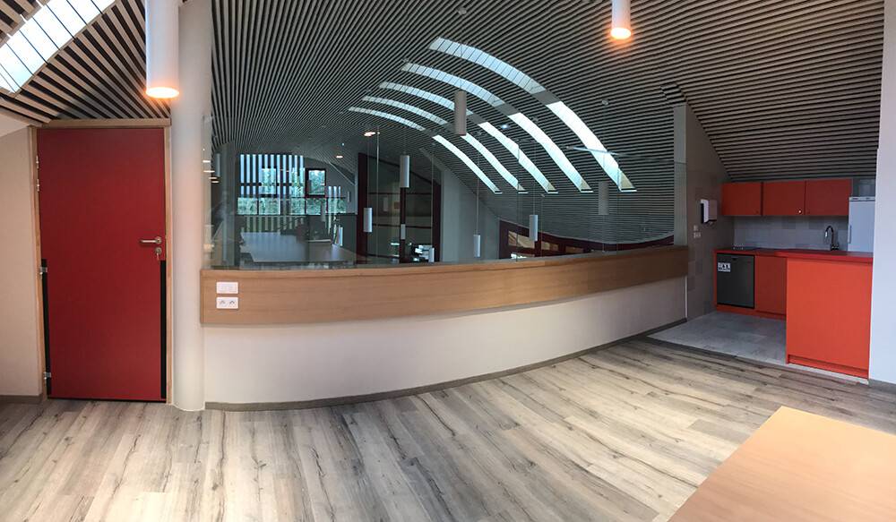 Banque d'accueil courbée en bois et verre dans un bâtiment public