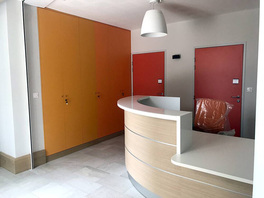 Banque d'accueil ovale et casiers orange dans cabinet médical