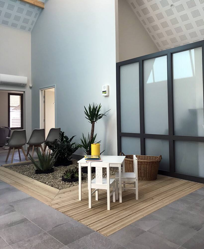 Patio intérieur végétalisé avec terrasse bois et verrière
