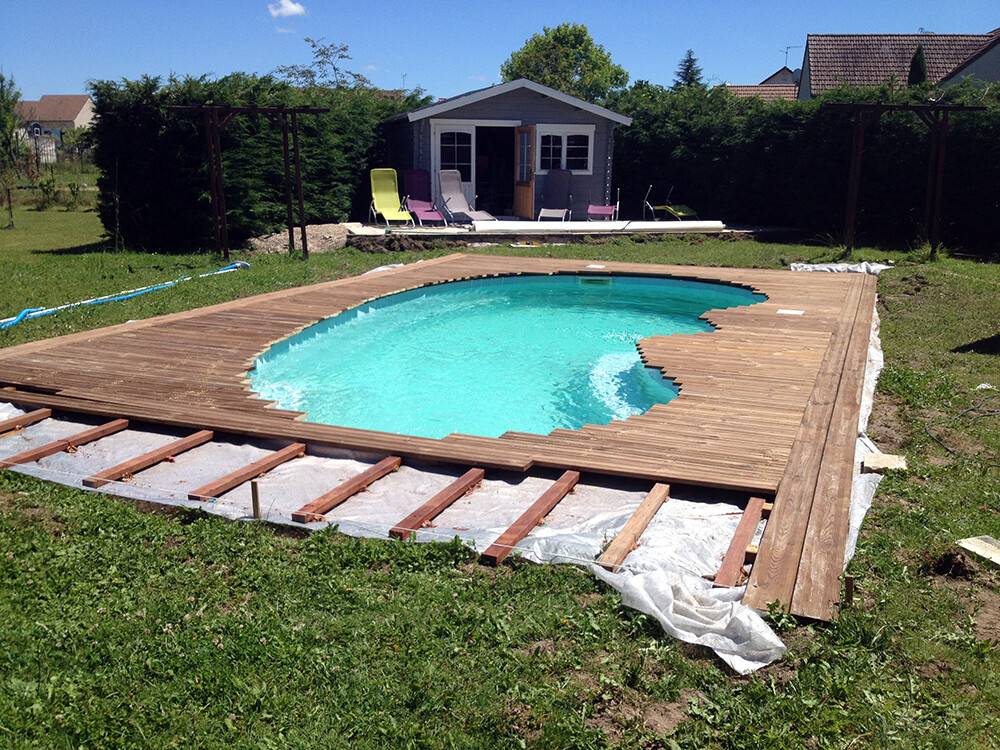 Pose de terrasse bois autour d'une piscine de forme arrondie