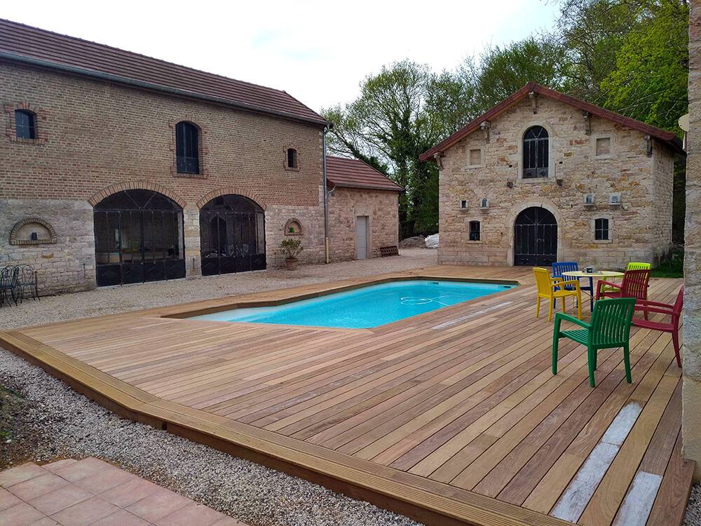 Plage de piscine en bois exotique dans cour pavée en pierre