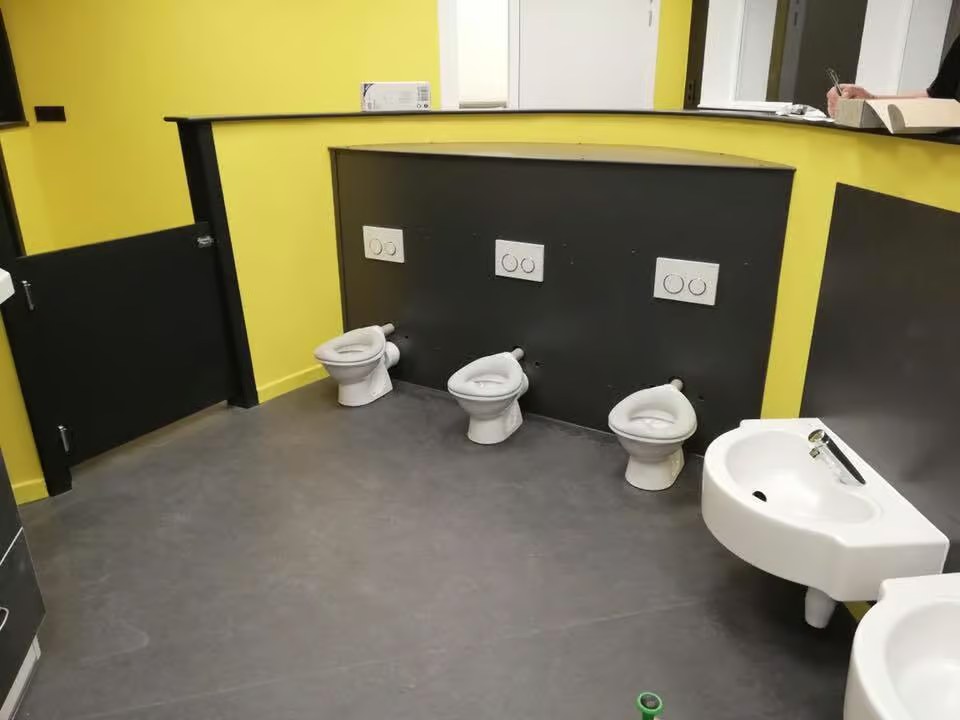 Sanitaires d'école avec mur jaune et toilettes pour enfants